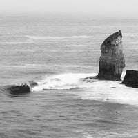 Lone sea stack rising from the Southern Ocean - Eyre Peninsula South Australia rugged coastline near Cummings Monument - black and white fine art coastal landscape photography - wave breaking at cliff base - Josh Whiting