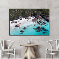 Black floating frame canvas print of turquoise water and granite boulders, bold large wall art for coastal interiors
